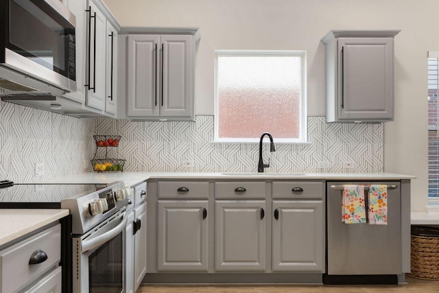 kitchen featuring stainless steel appliances, gray cabinets, and a sink