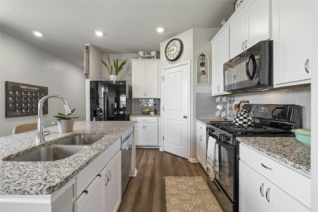 kitchen featuring tasteful backsplash, white cabinets, dark wood-type flooring, black appliances, and a sink