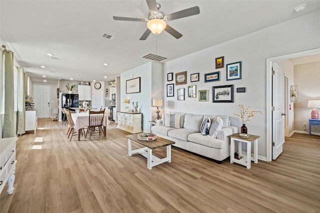 living area featuring a ceiling fan, visible vents, and light wood-style flooring