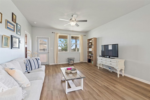 living room featuring wood finished floors, a ceiling fan, and baseboards