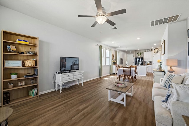 living area featuring baseboards, ceiling fan, visible vents, and wood finished floors