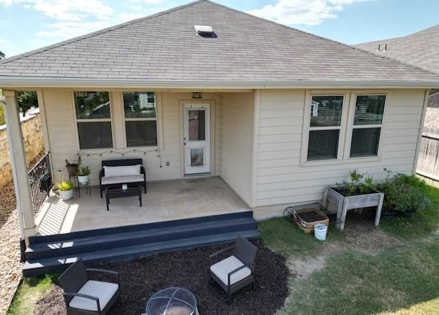 rear view of house featuring a patio area, fence, and roof with shingles