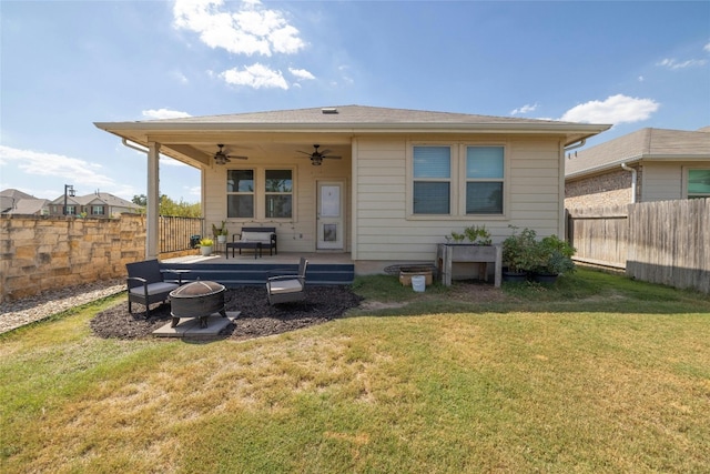 back of house featuring a ceiling fan, an outdoor fire pit, a lawn, and a fenced backyard