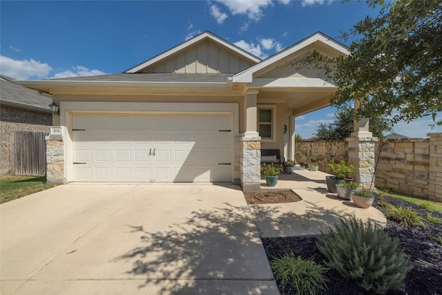 craftsman-style home featuring concrete driveway, board and batten siding, stone siding, and fence