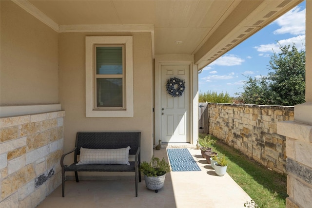 view of exterior entry with fence and stucco siding