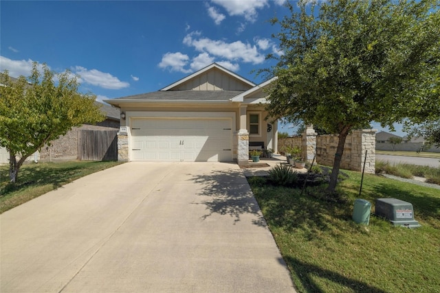 view of front of property with driveway, stone siding, an attached garage, fence, and board and batten siding