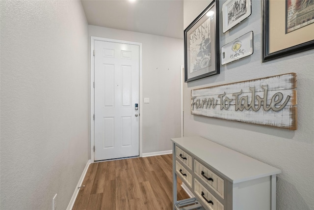 doorway to outside with baseboards and wood finished floors