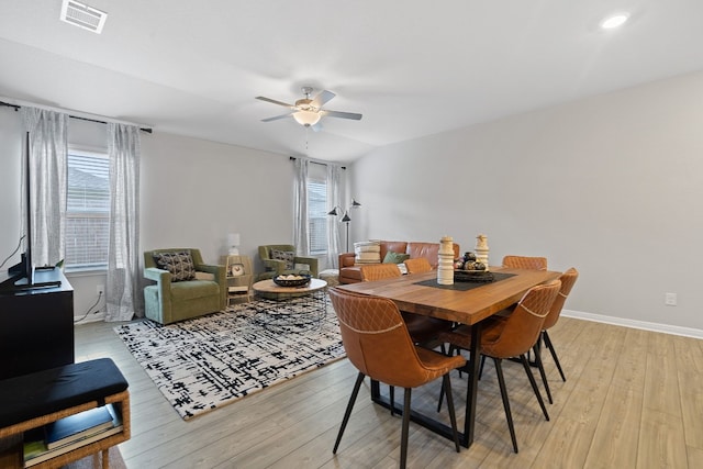 dining space featuring lofted ceiling, a ceiling fan, visible vents, baseboards, and light wood finished floors