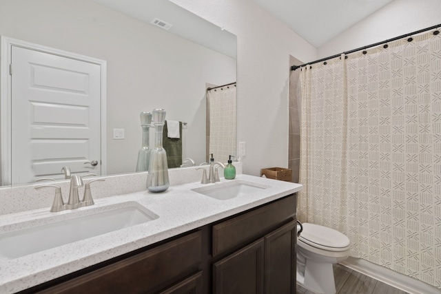 full bath with vaulted ceiling, double vanity, a sink, and toilet