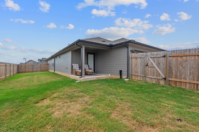 rear view of house with a fenced backyard, a gate, a patio, and a yard