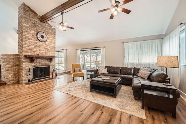 living area with beam ceiling, a fireplace, a ceiling fan, wood finished floors, and high vaulted ceiling