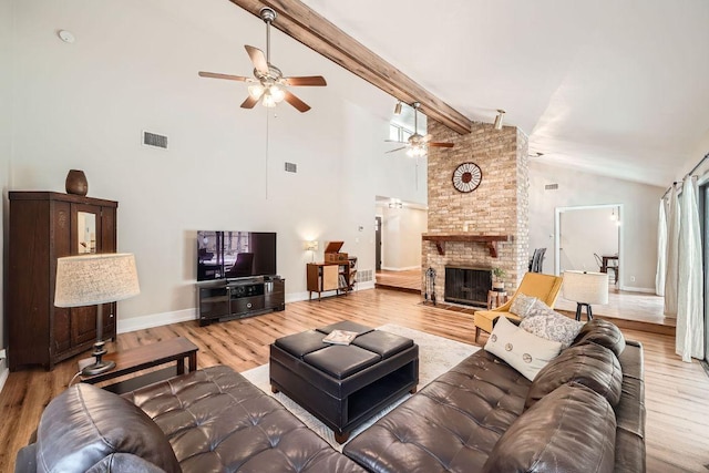 living room featuring beam ceiling, a fireplace, wood finished floors, and visible vents