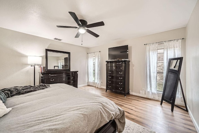 bedroom featuring ceiling fan, wood finished floors, visible vents, and baseboards