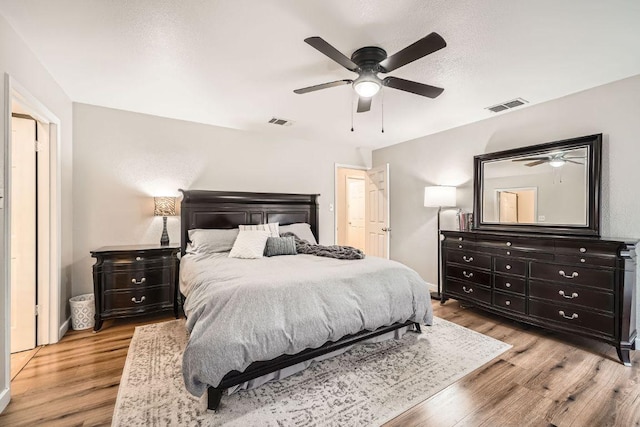 bedroom with light wood-type flooring, ceiling fan, and visible vents