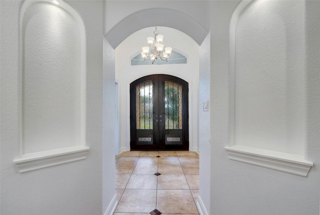 foyer entrance featuring light tile patterned floors, baseboards, arched walkways, an inviting chandelier, and french doors