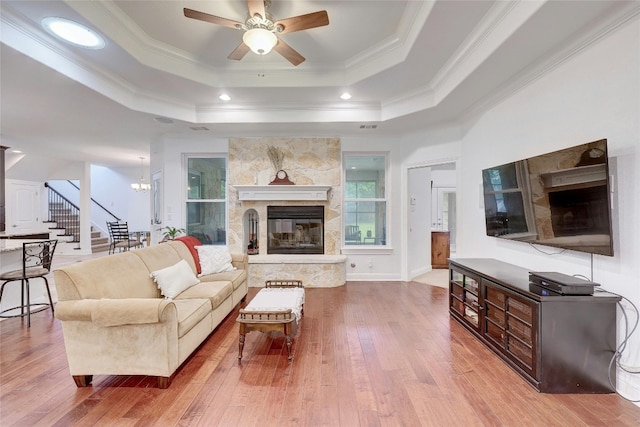 living room featuring ornamental molding, a tray ceiling, a fireplace, and hardwood / wood-style floors