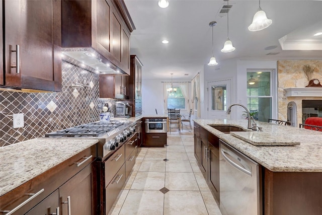 kitchen with tasteful backsplash, a center island with sink, appliances with stainless steel finishes, wall chimney range hood, and a sink