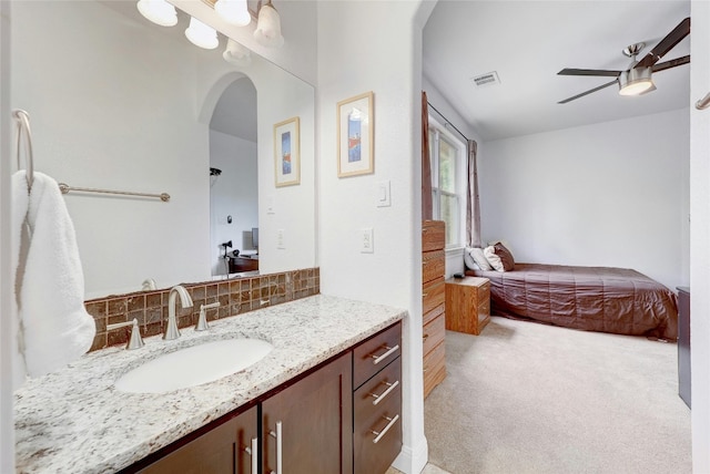 bathroom featuring visible vents, decorative backsplash, ceiling fan, vanity, and ensuite bath