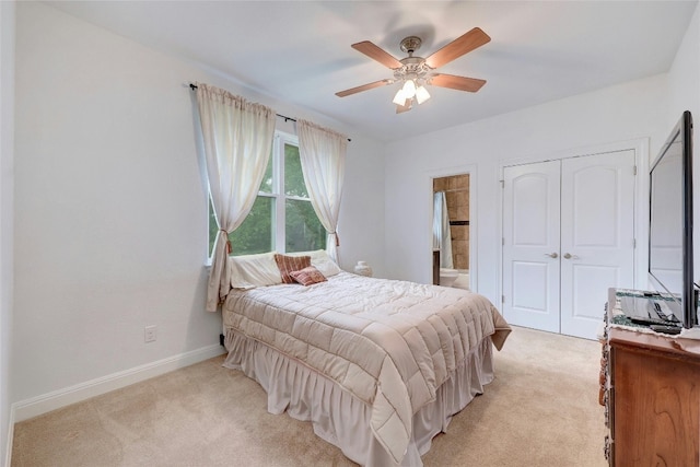 bedroom featuring a closet, light carpet, connected bathroom, ceiling fan, and baseboards