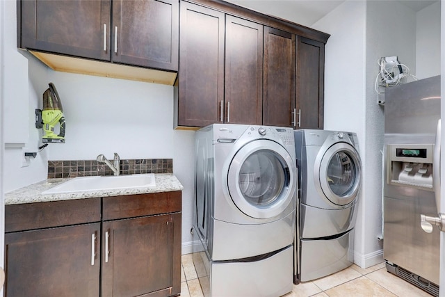 laundry area featuring light tile patterned flooring, a sink, cabinet space, and washer and dryer