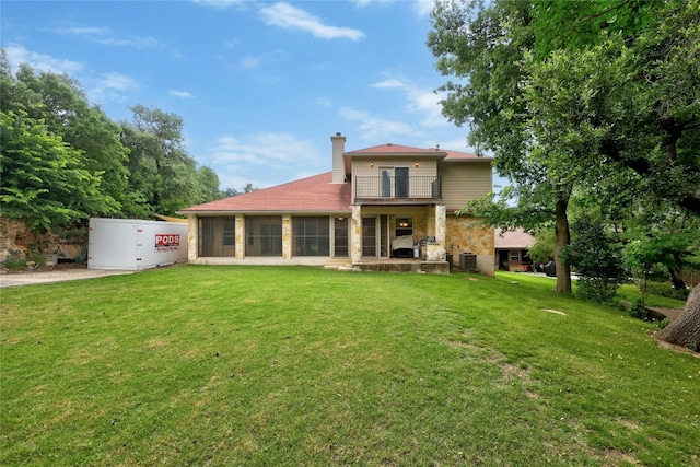 back of house featuring a sunroom, a chimney, a yard, and a balcony