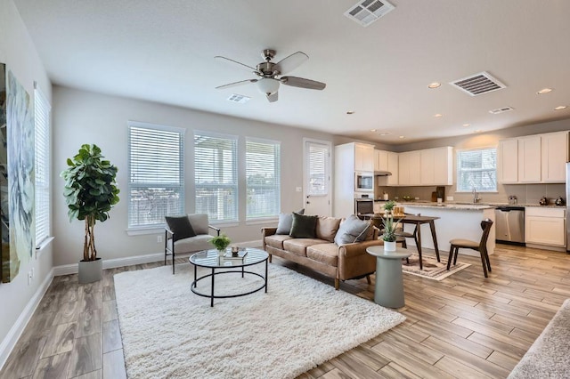 living area with light wood-type flooring, visible vents, and recessed lighting