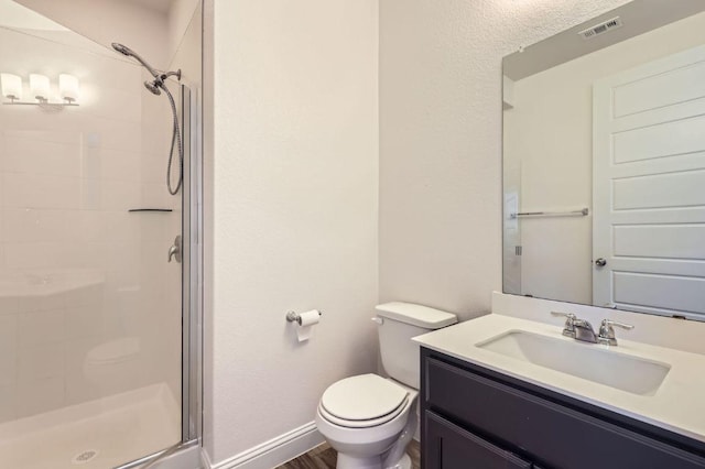 bathroom with visible vents, toilet, a shower stall, vanity, and baseboards