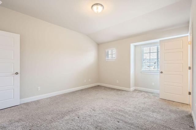 spare room with carpet floors, lofted ceiling, and baseboards