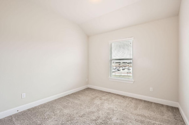 carpeted spare room with vaulted ceiling and baseboards