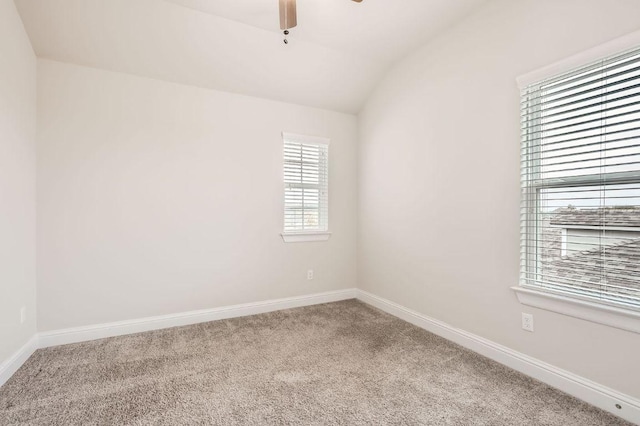 carpeted empty room with vaulted ceiling, ceiling fan, and baseboards