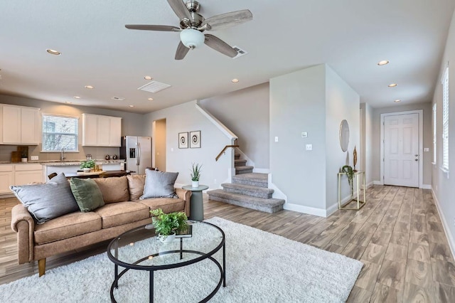 living room with light wood-type flooring, baseboards, stairway, and recessed lighting