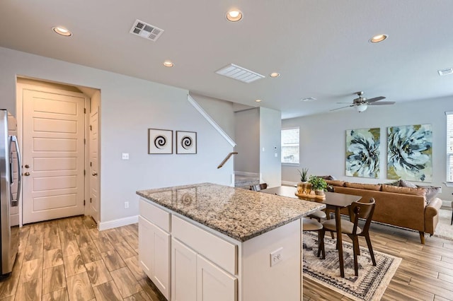 kitchen with recessed lighting, white cabinetry, visible vents, and a center island