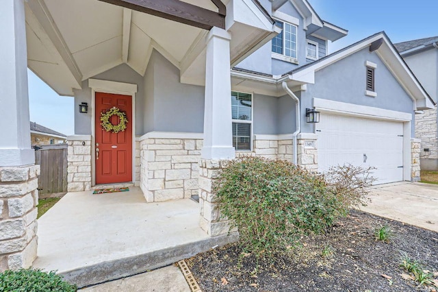 doorway to property with a garage, stone siding, driveway, and stucco siding