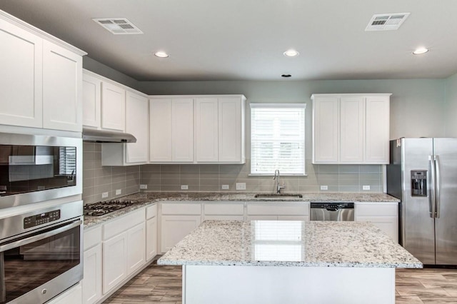 kitchen featuring stainless steel appliances, a sink, visible vents, and under cabinet range hood