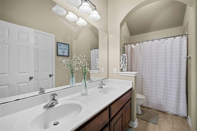 bathroom with tile patterned floors, a sink, toilet, and double vanity