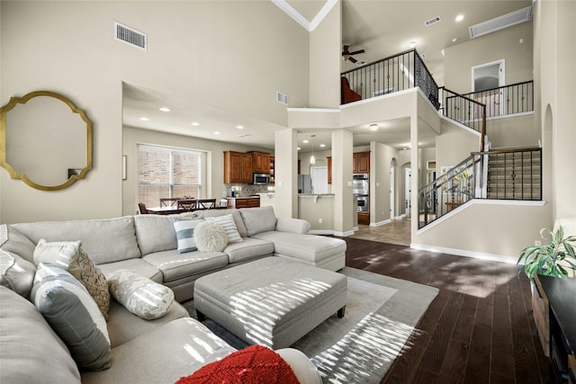 living room with stairs, dark wood-type flooring, arched walkways, and visible vents