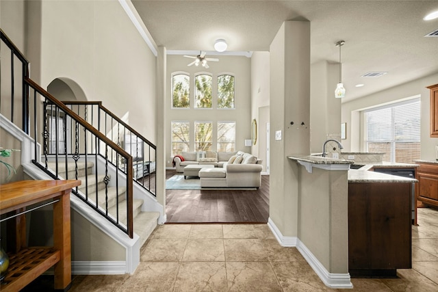 interior space with light stone countertops, baseboards, a high ceiling, and visible vents