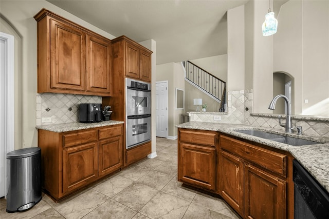 kitchen featuring brown cabinets, black dishwasher, double oven, and a sink