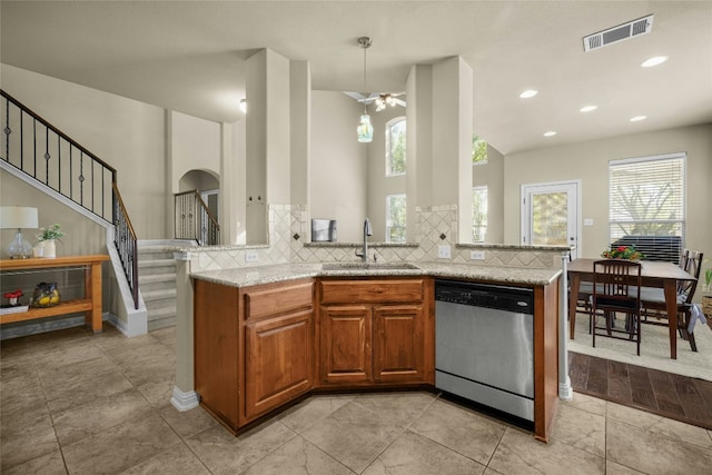 kitchen with light stone counters, a sink, visible vents, stainless steel dishwasher, and tasteful backsplash