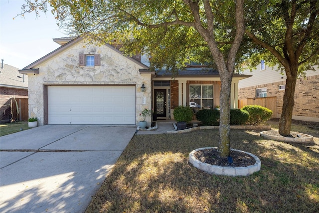 view of front of house featuring driveway, stone siding, an attached garage, and fence