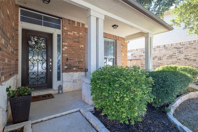 entrance to property featuring covered porch and brick siding