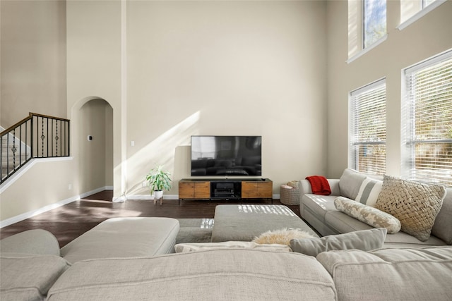 living room featuring arched walkways, wood finished floors, plenty of natural light, and stairs