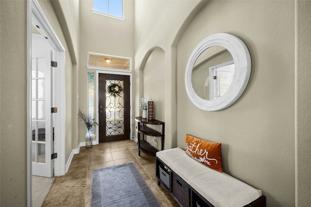 entrance foyer featuring a towering ceiling, baseboards, and tile patterned floors