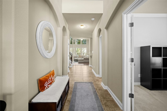 hallway with baseboards, carpet, and tile patterned floors