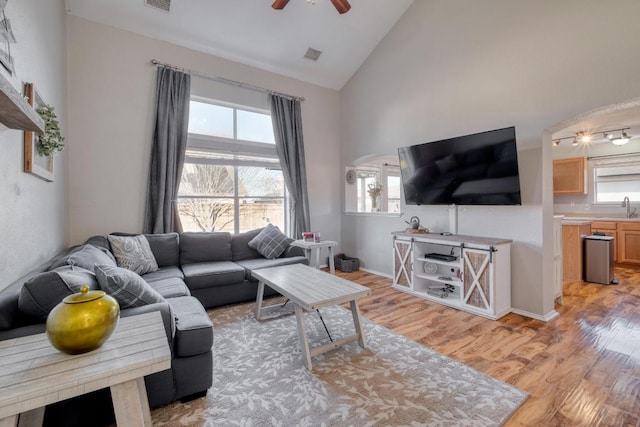 living room featuring light wood-style floors, visible vents, and high vaulted ceiling