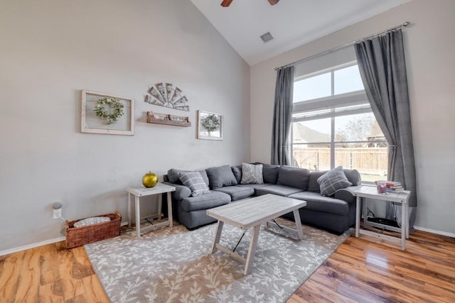 living room with baseboards, visible vents, ceiling fan, wood finished floors, and high vaulted ceiling