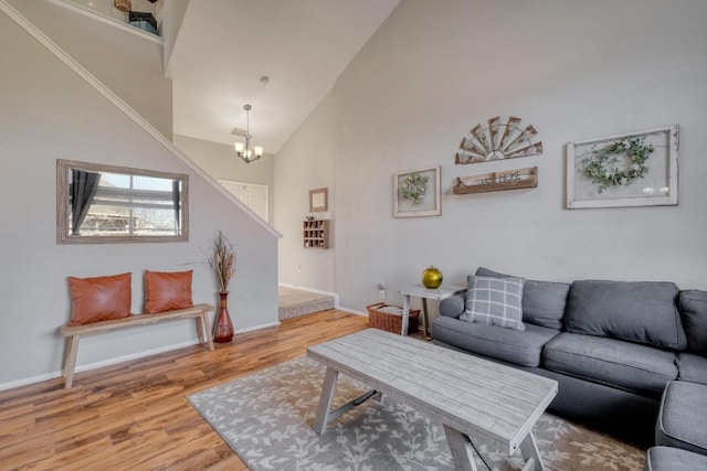 living area with baseboards, a notable chandelier, high vaulted ceiling, and wood finished floors