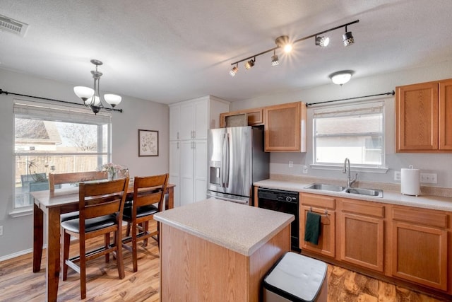 kitchen with light countertops, black dishwasher, stainless steel fridge, and a sink