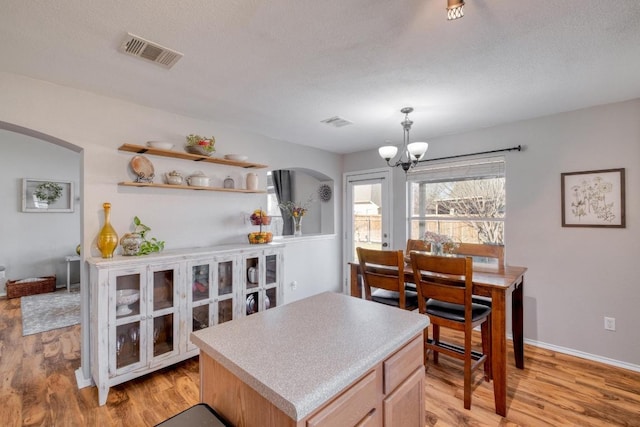 kitchen featuring visible vents, arched walkways, a center island, light wood-type flooring, and a chandelier