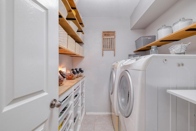 clothes washing area with light tile patterned floors, laundry area, washing machine and clothes dryer, and baseboards